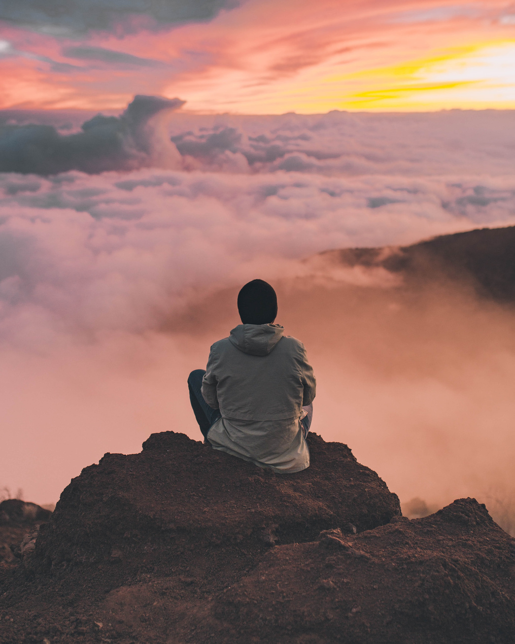 Person Sitting on Top of a Mountain at Sunrise 
